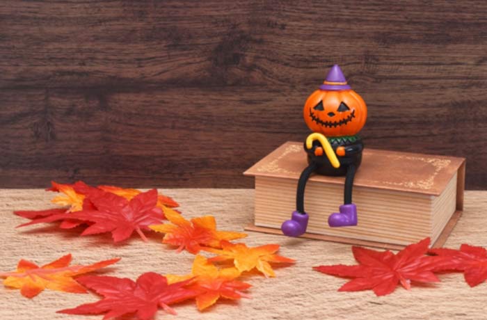 ハロウィンのかぼちゃの人形と紅葉の落ち葉、秋の季節感を表す写真